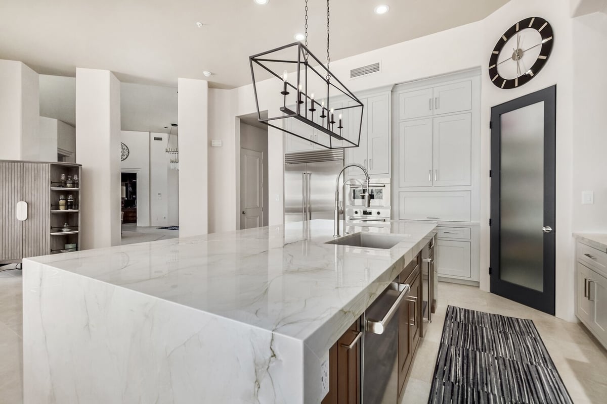 Oversized kitchen island with modern faucet and stainless fridge by Kitchens by Good Guys in Mesa, AZ.