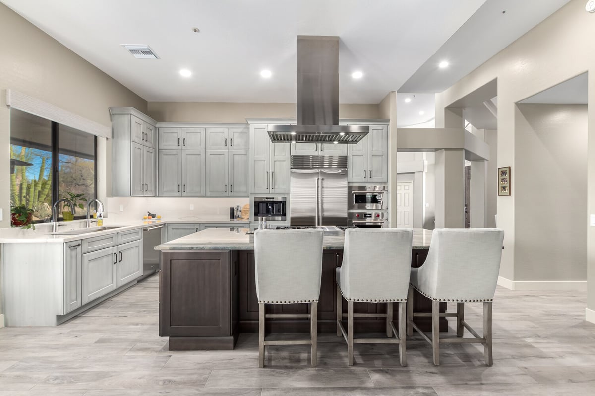 Rear kitchen view with marble island and stainless range by Kitchens by Good Guys in Glendale, AZ.