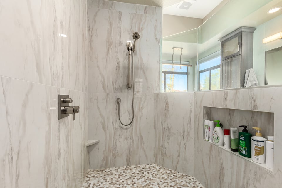 Walk-in shower with marble tile and niche storage by Kitchens by Good Guys in Fountain Hills, AZ.