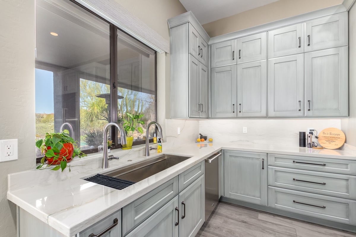Window-lit kitchen corner with dual sinks and soft gray cabinetry by Kitchens by Good Guys in Scottsdale, AZ.