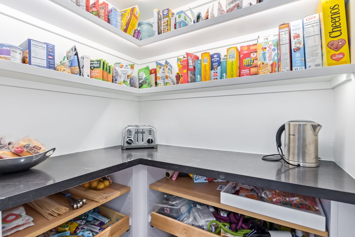 Walk-in pantry with black countertops and open shelving in Scottsdale custom home by Kitchens by Good Guys.