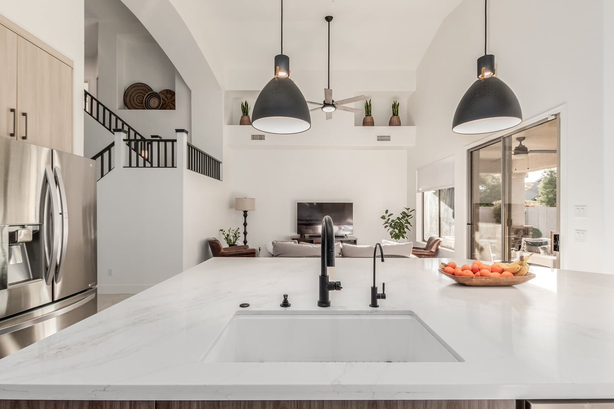Kitchen view with modern pendant lights and living space in Rio Verde home by Kitchens by Good Guys.