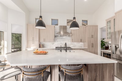 Modern kitchen design with black pendants and stainless hood in Phoenix, AZ by Kitchens by Good Guys.