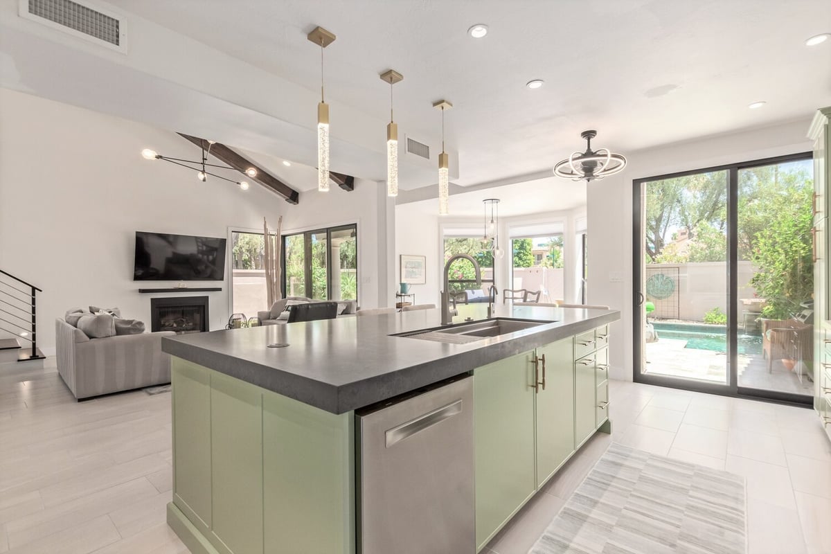 Open-concept Scottsdale custom home kitchen with sage green island and pool views by Kitchens by Good Guys.