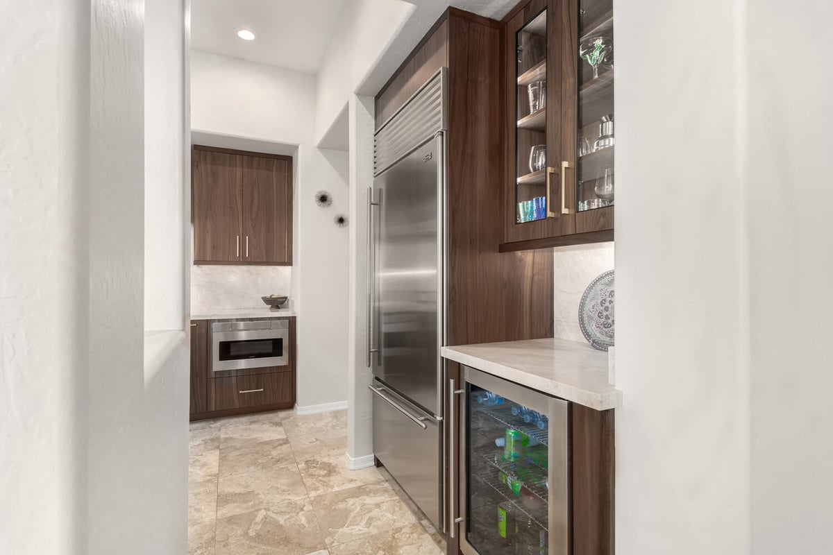 Beverage station with glass cabinetry and stainless fridge in Fountain Hills custom home by Kitchens by Good Guys.