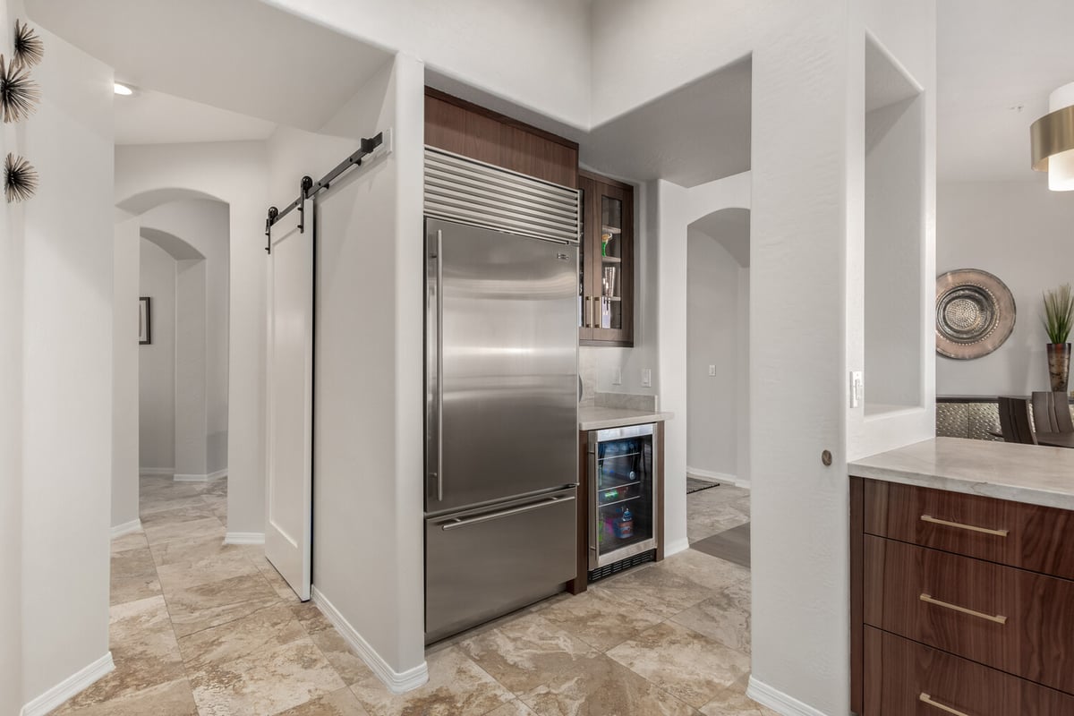 Modern pantry and refrigerator area with wine fridge in a Fountain Hills home by Kitchens by Good Guys.