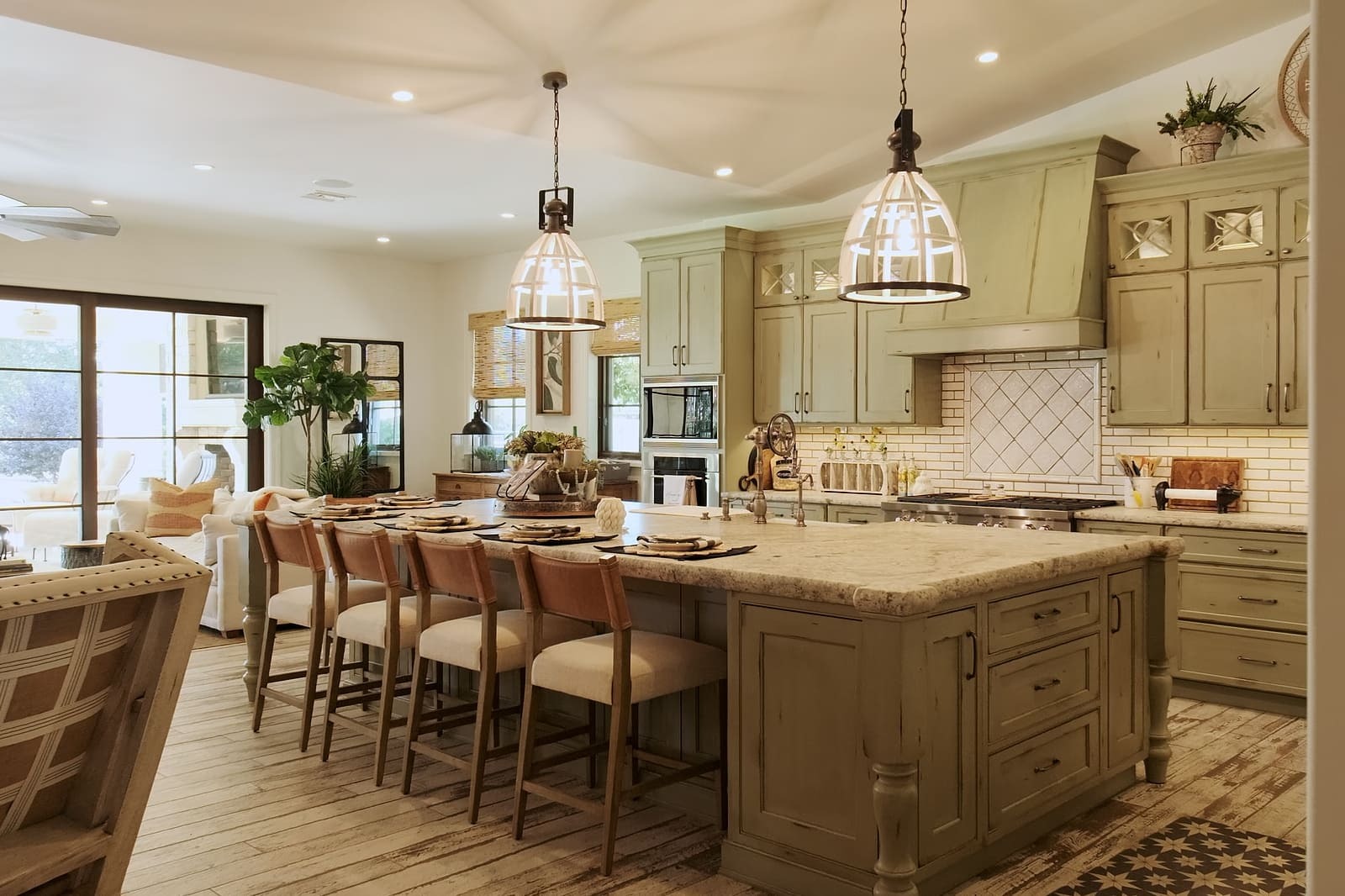 Spacious luxury kitchen remodel with oversized island, sage cabinetry, pendant lights, and open-concept seating area.