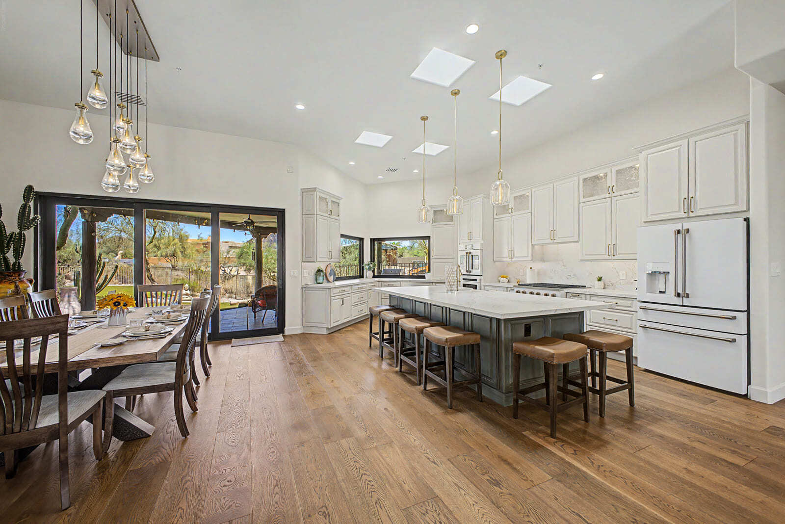 Bright kitchen remodel with large island, white cabinetry, pendant lights, and sliding glass doors.