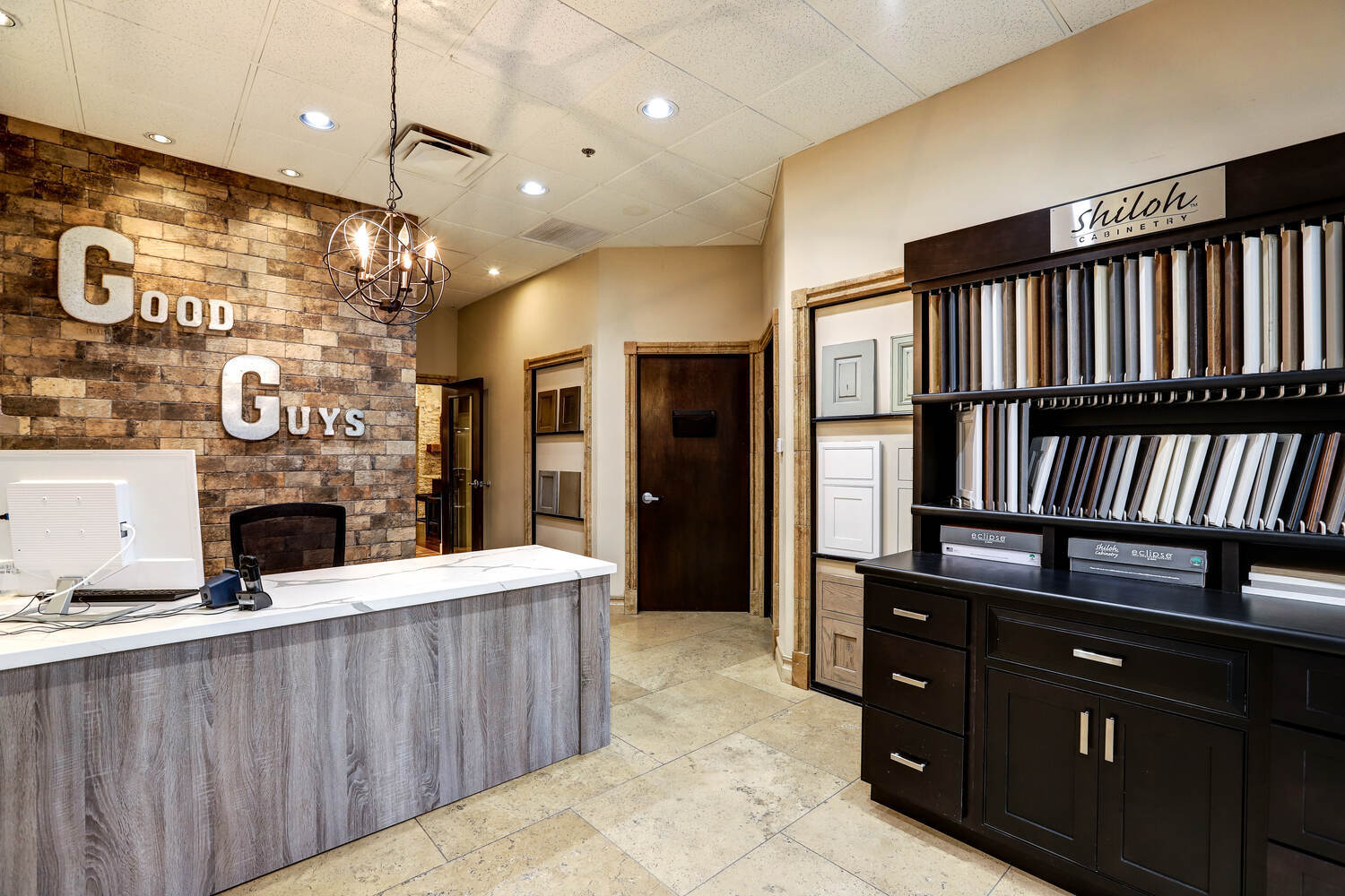 Front desk at Kitchens by Good Guys showroom surrounded by cabinetry samples and warm design elements