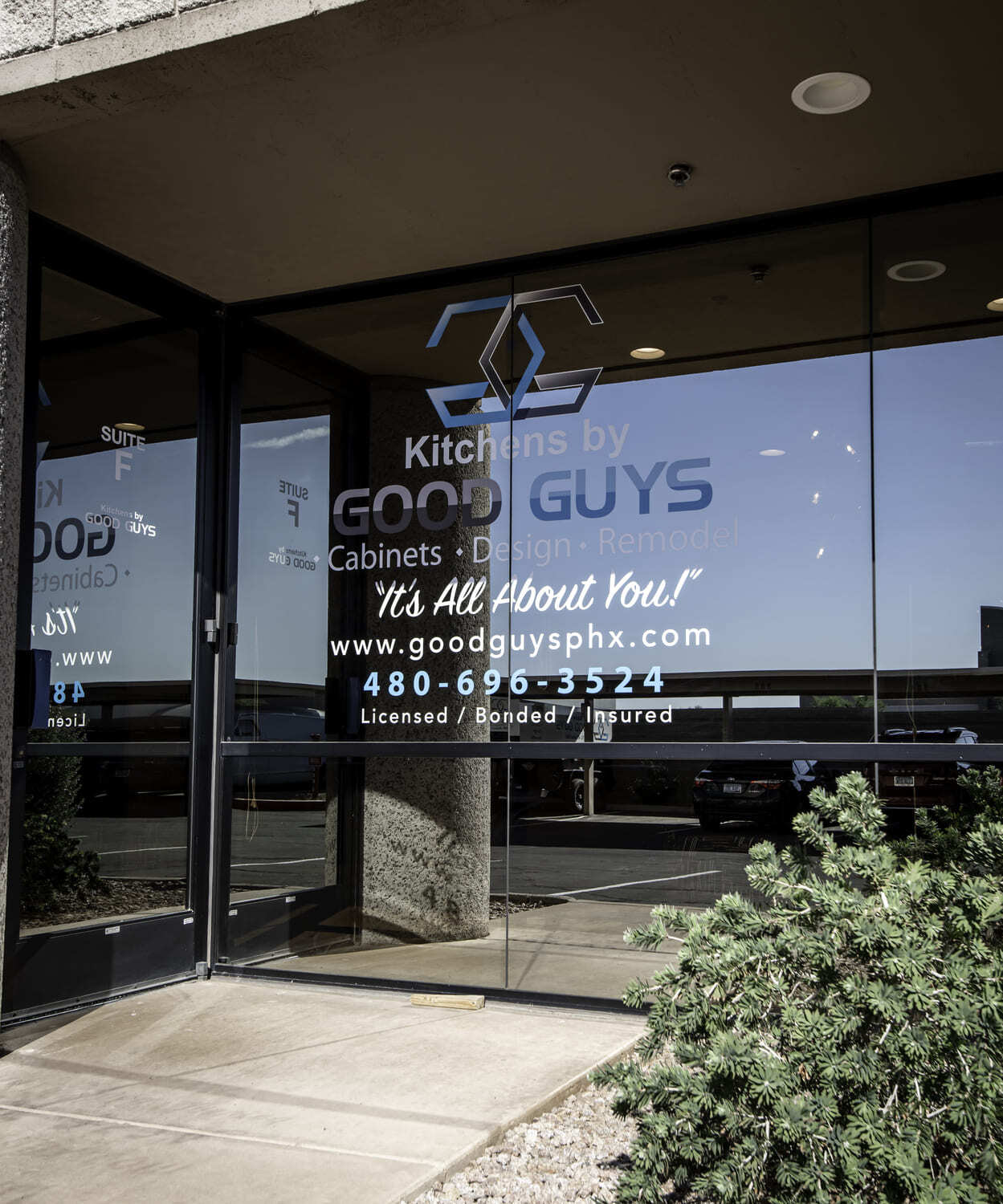 Showroom entrance with Kitchens by Good Guys logo and business details on glass windows and door.